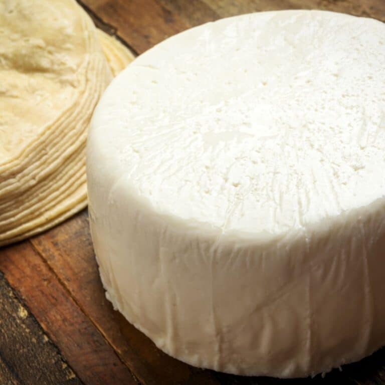 Square image of queso fresco on a cutting board.