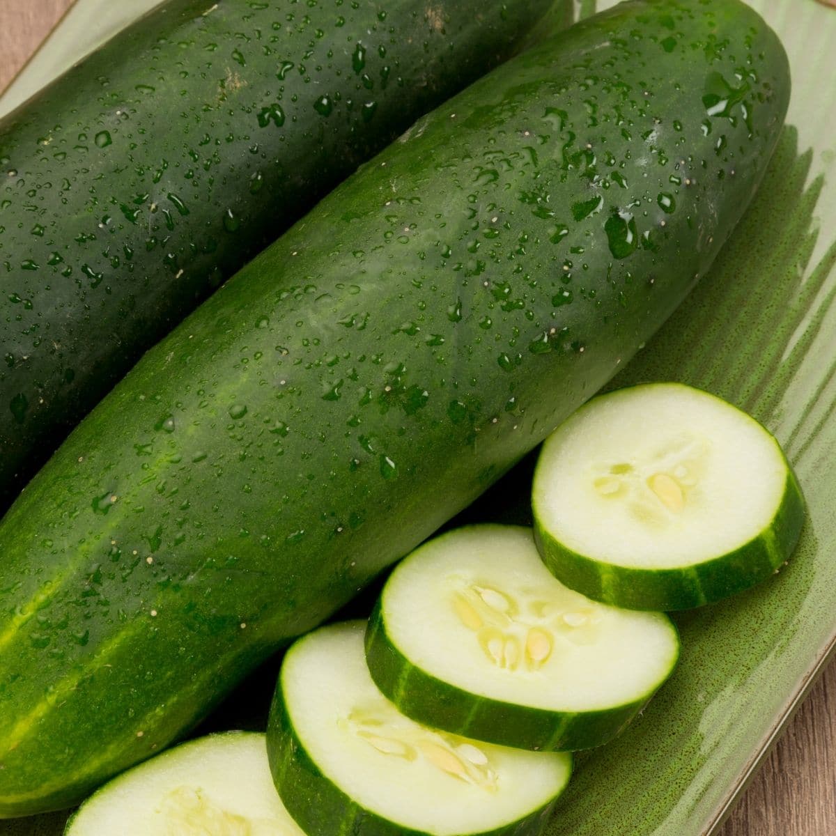 Square image of cucumbers on a cutting board.