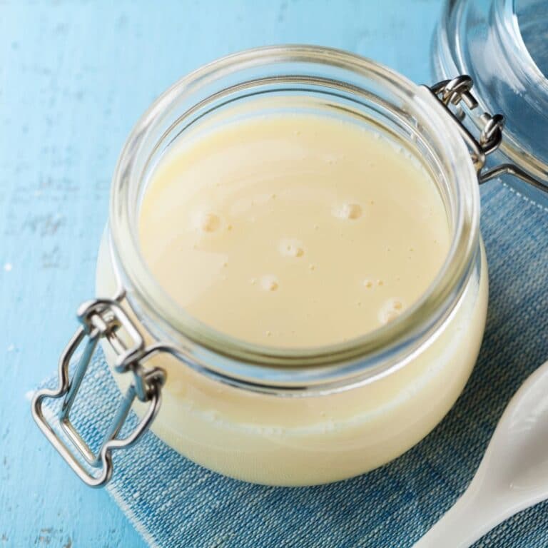 Square image of evaporated milk in a glass container.