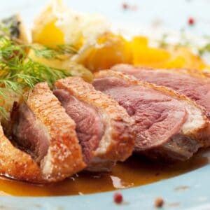 Square image of sliced duck breast on a plate.