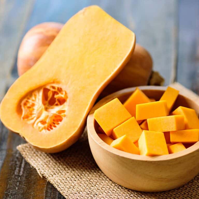 Square image of butternut squash in a bowl and sliced.
