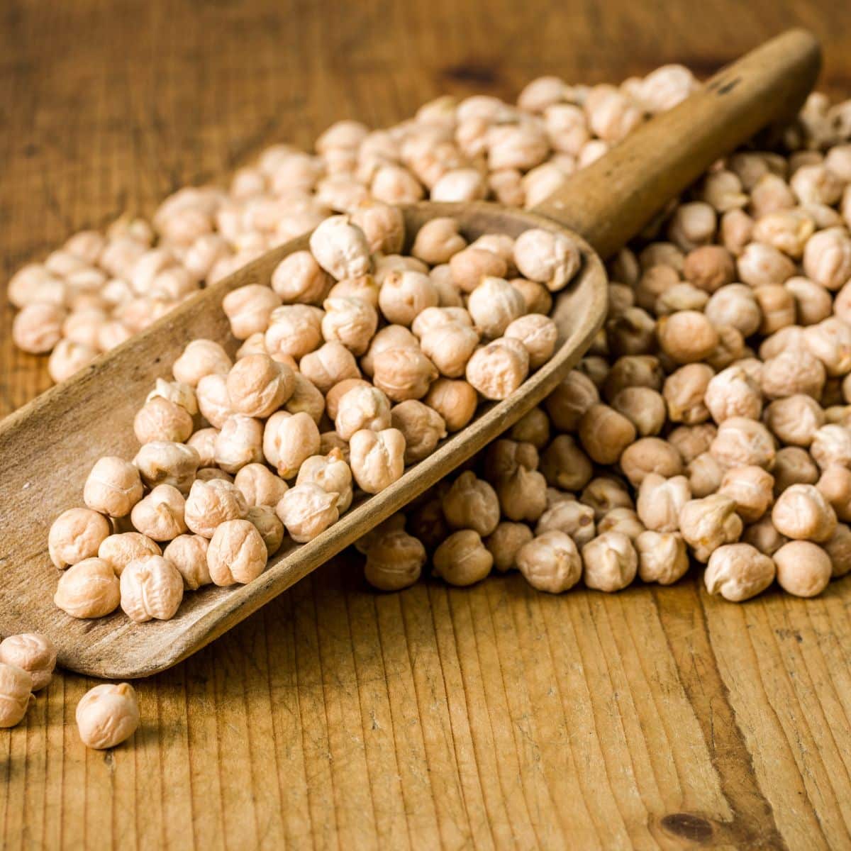 Square image of chickpeas on a wooden background.
