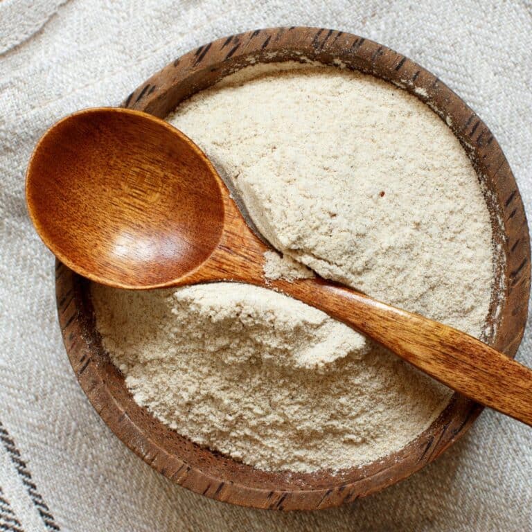 Square image of teff flour in a wooden bowl.